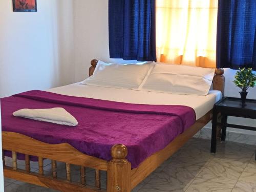 1 cama con marco de madera y manta morada en Coorg Get Inn Home Stay, en Madikeri