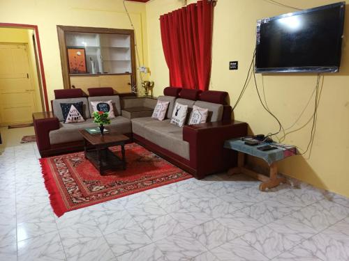 sala de estar con sofá y TV de pantalla plana en Coorg Get Inn Home Stay, en Madikeri