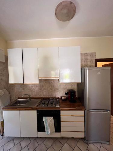 a kitchen with white cabinets and a stainless steel refrigerator at Villa Gianna in Taranto