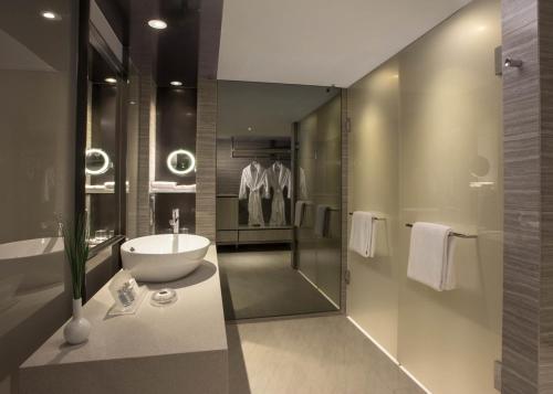 ein Bad mit einem Waschbecken, einer Dusche und einem Waschbecken in der Unterkunft Carlton Hotel Singapore in Singapur