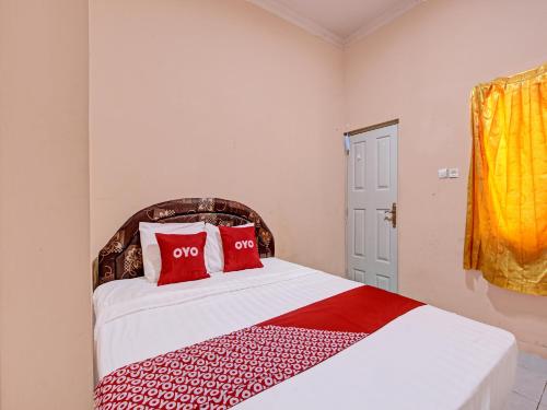 Un dormitorio con una cama con almohadas rojas. en OYO 92459 Cahyo Kost 2 en Semarang