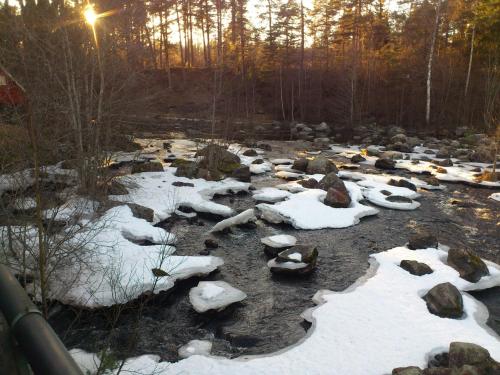 a river covered in snow with rocks and trees at Ruth's bed and own breakfast in Skutskär