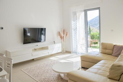 sala de estar blanca con TV y sofá en Lavandar Bay C03, en Kotor