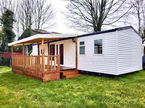 a white tiny house with a porch and a deck at Mobil Home Le Berlin in Noyelles-sur-Mer
