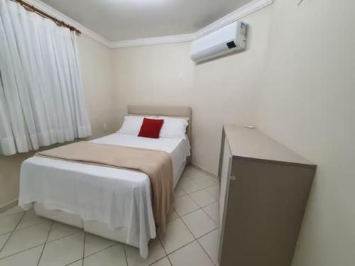 - une petite chambre avec un lit et un oreiller rouge dans l'établissement Apartamento Completo Frente Praia de Itaparica, à Vila Velha
