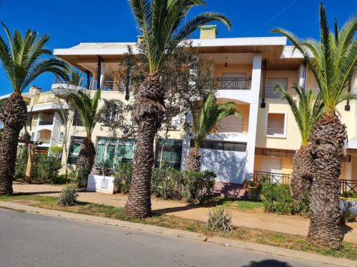 a row of palm trees in front of a building at Appartement Bouznika Bay Golf in Bouznika