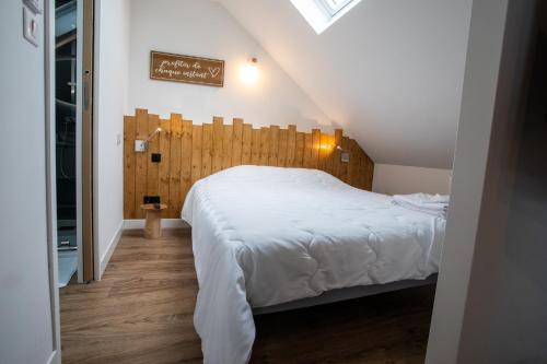 a bedroom with a large white bed with a wooden headboard at Escapade Eudoise in Eu