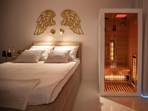 a bedroom with a bed with angel wings on the wall at Apartament Gold SAUNA&JACUZZI Kołobrzeg in Kołobrzeg