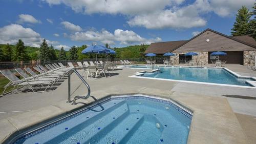 una gran piscina con sillas y sombrillas en Seven Springs Sunridge 2 Bedroom Standard Condo - Ski In Out, Pet Friendly! condo en Champion