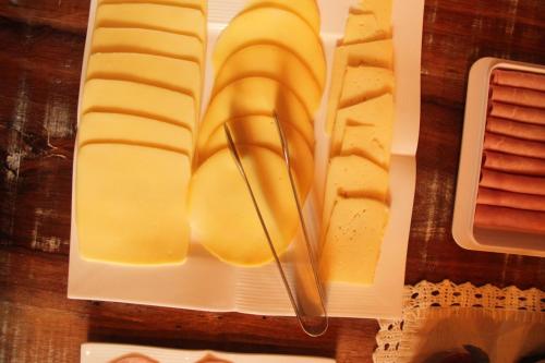 a plate of cheese and a knife on a cutting board at Pousada Vila dos Butias in Urubici