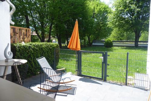 um guarda-chuva laranja e duas cadeiras ao lado de uma cerca em Maurers Schlierseetraum 6, Studio 455 mit 42 qm neu renoviert, Erdgeschoss mit eingezäunter Terrasse in ruhiger Lage am Kirchbichlweg 8 em Schliersee