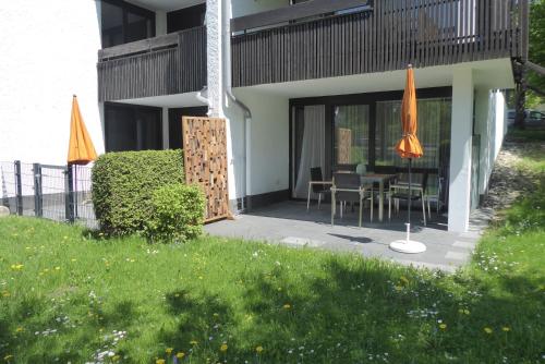 a patio with a table and chairs and umbrellas at Maurers Schlierseetraum 6, Studio 455 mit 42 qm neu renoviert, Erdgeschoss mit eingezäunter Terrasse in ruhiger Lage am Kirchbichlweg 8 in Schliersee