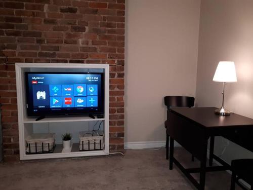 a flat screen tv sitting in a living room with a table at Bauer Terrace - Cozy 1 bedroom beside The Citadel in Halifax