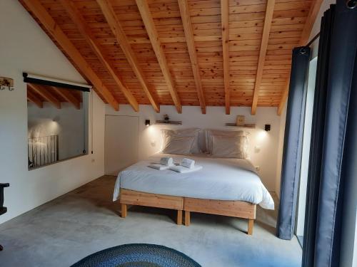 Schlafzimmer mit einem Bett mit Holzdecke in der Unterkunft Casa de Santo Amaro in Santo Amaro