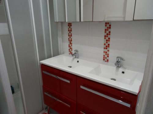 baño con lavabo blanco y azulejos rojos en Maison d'hôtes les roses trémières, en Saclay