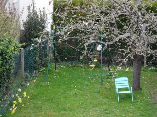 a green chair in a yard with a tree at Maison d'hôtes les roses trémières in Saclay