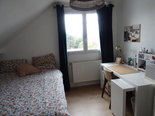 1 dormitorio con cama, escritorio y ventana en Maison d'hôtes les roses trémières, en Saclay