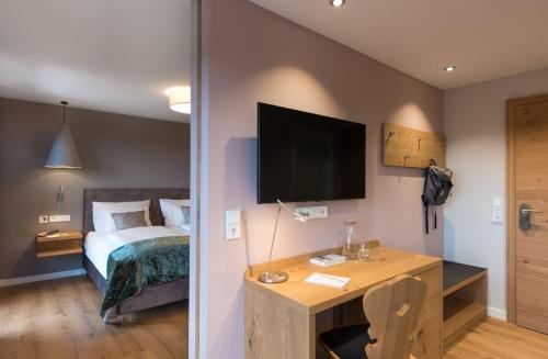 a bedroom with a bed and a desk with a television at Natur- & Genießerhotel Der Birkenhof in Oberstaufen