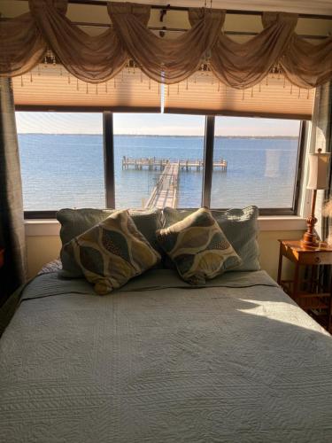 a bed with pillows in front of a large window at Romantic Island condo for 2 - Sunset Harbor 1-205 - Navarre Beach in Navarre