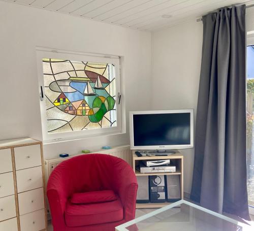 ein Wohnzimmer mit einem roten Stuhl und einem Buntglasfenster in der Unterkunft 1008 - Bungalow Ziegenbalg in Dahme