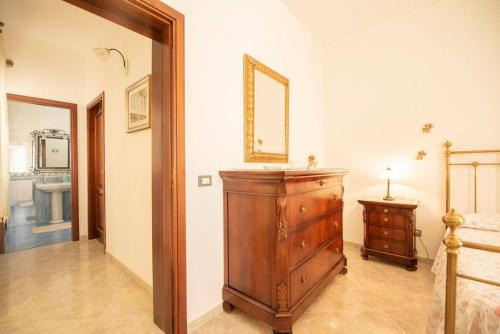 Cette chambre comprend une commode en bois et un miroir. dans l'établissement A pochi passi dal mare, à San Vito Lo Capo