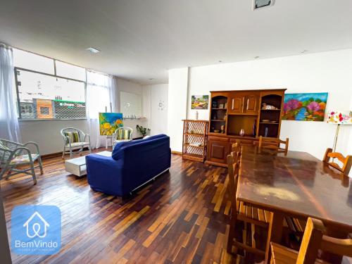 a living room with a table and a blue chair at Apartamento completo em frente ao Farol da Barra in Salvador