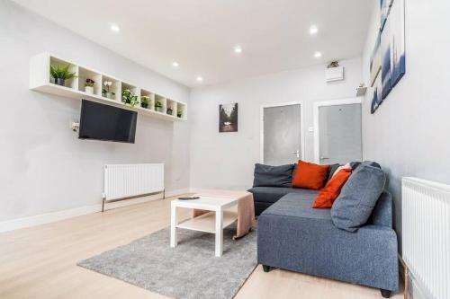 ein Wohnzimmer mit einem blauen Sofa und einem Fernseher in der Unterkunft Lavish 2- bedroom Flat with Free Parking in Birmingham