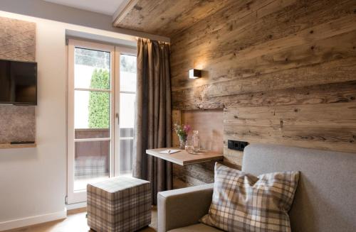 a living room with wooden walls and a couch and a window at Natur- & Genießerhotel Der Birkenhof in Oberstaufen