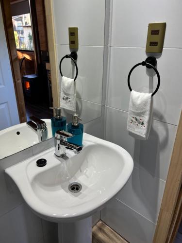 La salle de bains est pourvue d'un lavabo blanc et d'un miroir. dans l'établissement CABAÑAS QATAR PUCÓN, à Pucón