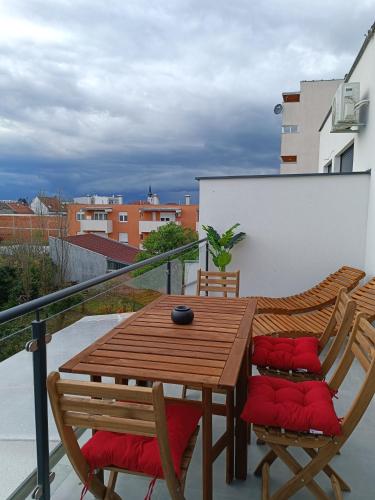 a wooden table and chairs on a balcony at Tesla Point in Osijek