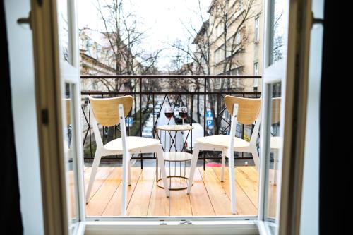 un balcón con 2 sillas y una mesa con botellas de vino. en CracWoW Saint Sebastian Apartments, en Cracovia