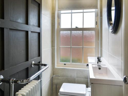 a bathroom with a toilet and a sink and a window at Loyal Cerise Bondgate in Selby