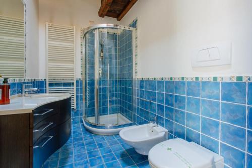a blue tiled bathroom with a toilet and a shower at Yourbanflat Dante in Padova