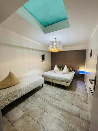 Cette chambre comprend deux lits et un plafond orné d'un lustre. dans l'établissement Flat on 2 floors near stade de france, à Aubervilliers