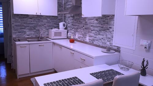 a kitchen with white cabinets and a microwave at Penzión Florens, Nesvady in Nesvady