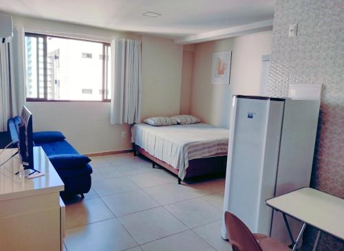 um pequeno quarto com uma cama e um frigorífico em Home Boa Viagem no Recife