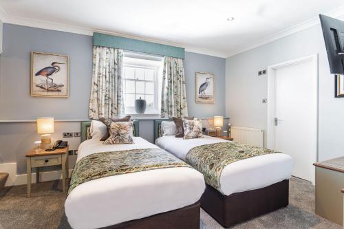a hotel room with two beds and a window at The Manor Coastal Hotel & Inn, Blakeney - The Coaching Inn Group in Blakeney