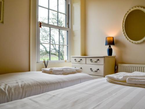 a bedroom with two beds and a window and a mirror at The Old Vicarage in Westward