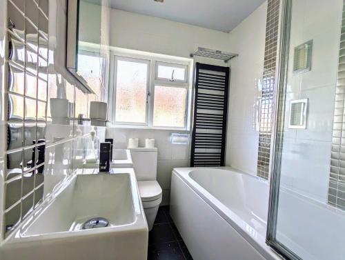 a bathroom with a tub and a toilet and a sink at Stunning 4BR House with Free Parking - By INNit in Brighton & Hove