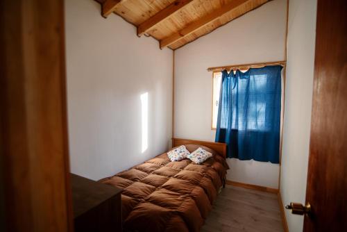 een bed in een kamer met een blauw gordijn bij cabañas camino al totoral in El Quisco