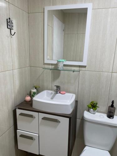 uma casa de banho com um lavatório, um WC e um espelho. em Ohana 1 em Puerto Iguazú