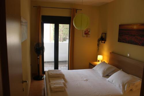 a bedroom with a bed with white sheets and a window at T&A Apartment,near the sea. in Marathón