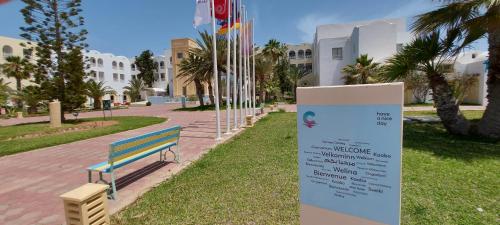 a park bench with a sign in front of a building at Calimera Yati Beach in Midoun