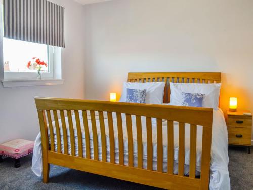 um quarto com uma cama de madeira e uma janela em India Lane Cottage em Montrose