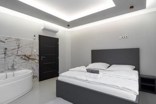 a white bedroom with a bed and a bathtub and a bath tub at OŽA apartmány in Ostrava