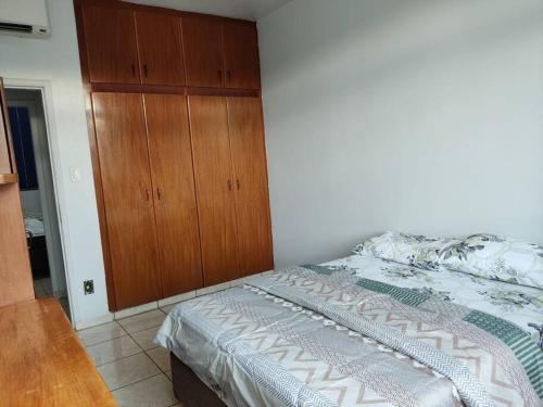 a bedroom with a bed and a wooden cabinet at Apartamento 2 quartos Setor Sul in Goiânia