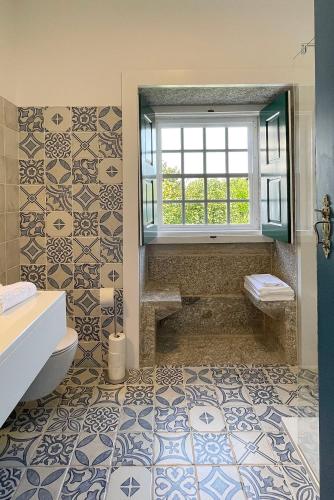 a bathroom with a toilet and a window and tiles at Casa da Agrela in Ponte da Barca