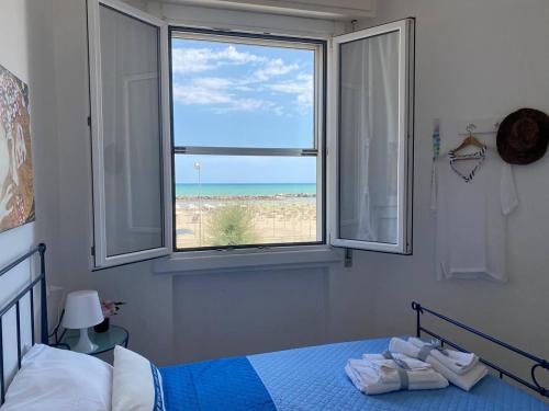 - une chambre avec un lit et une fenêtre donnant sur la plage dans l'établissement SeaSound Casa Vacanze, à Rimini