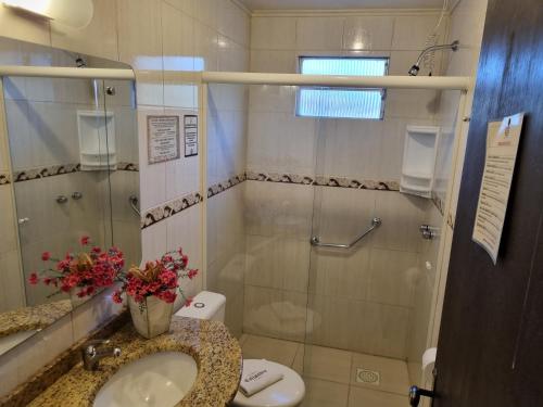 a bathroom with a shower and a sink and a toilet at Pousada Caliandra Da Serra in Canela