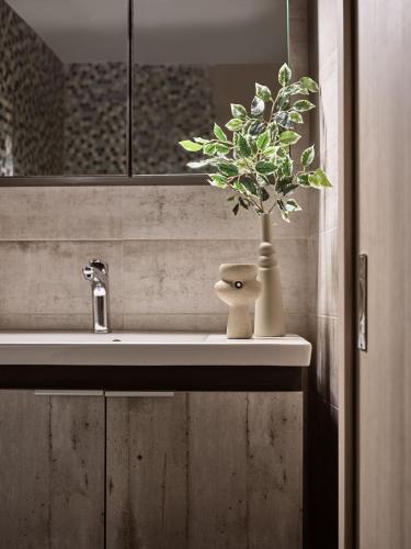 a bathroom sink with a plant in a vase on it at Laura Suites in Zakynthos Town